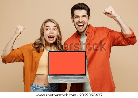 Young happy couple two friend family IT man woman wear casual clothes hold use work on blank screen laptop pc computer together do winner gesture isolated on pastel plain light beige color background