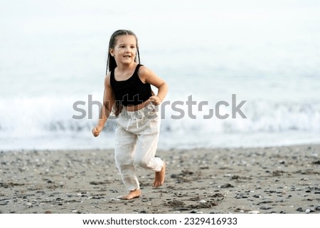 Cute smiling little girl running on the beach, having fun. Travel vacation, summer concept