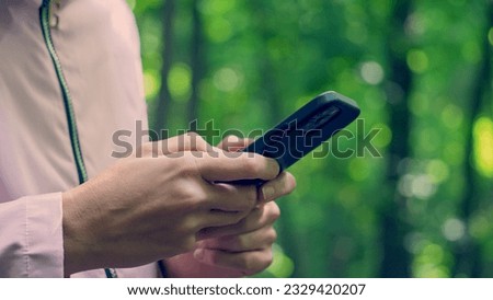 Close-up of female hands using mobile phone. Young active woman uses smartphone for navigation while hiking, traveling in nature. Modern technologies for an active and healthy lifestyle.