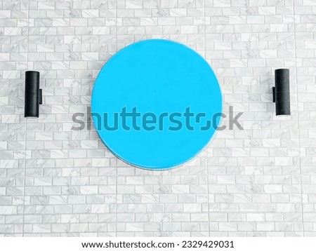 Blank Blue signboard on a marble tile laminate wall of building. Round banner on marble brick wall. Blue circle signboard for logo. Empty Blue circular sign hanging on a wall
