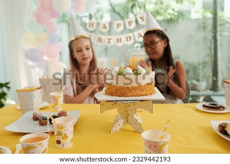 Birthday party guests clapping to decorated cake brought to table