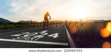 New year 2024 or start straight and beginning concept.silhouette of Blurry Man ride on bike and word 2024 start written on the road at sunset.Concept of challenge or career path,business strategy. Royalty-Free Stock Photo #2329447191