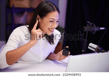 Cheerful blogger filming herself testing new model of earbuds