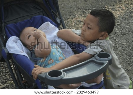 older brother is playing with his younger brother in the stroller