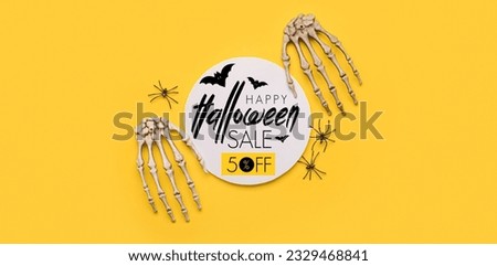 Paper with text HAPPY HALLOWEEN SALE, spiders and skeleton hands on yellow background