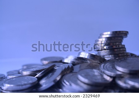 A pile of coins on a blue background. Shallow depth of field on "coin tower". Royalty-Free Stock Photo #2329469