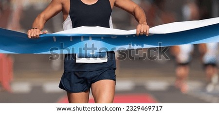 Man running towards the finish line, male runner win the race outdoor in the city. Passes finish line as a winner Royalty-Free Stock Photo #2329469717
