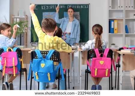 Little pupils with backpacks having lesson in classroom, back view