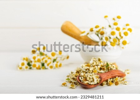 Dried chamomile tea on texture table.dry chamomile. Chamomile tea. flat lay. Composition with a bouquet and chamomile inflorescences in a mortar. Herbal drink. Soothing and tonic tea. copy space. Royalty-Free Stock Photo #2329481211