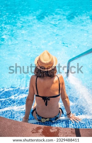 Young woman relaxing in pool at spa resort on vacation. Summer relaxing concept