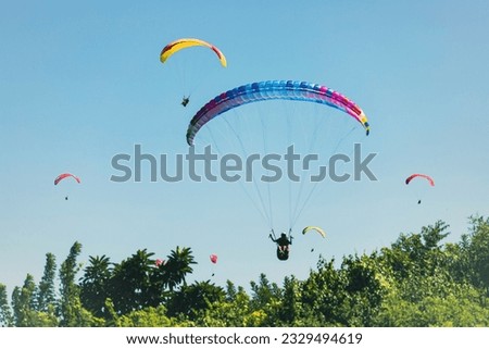 Paraglider in the blue sky. The sportsman flying on a paraglider. Royalty-Free Stock Photo #2329494619