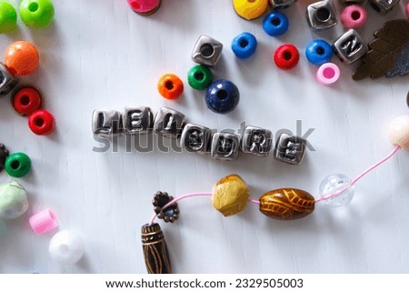 Word leisure made from colored beads on the thread, concept of designing or occupation of hand made, light background