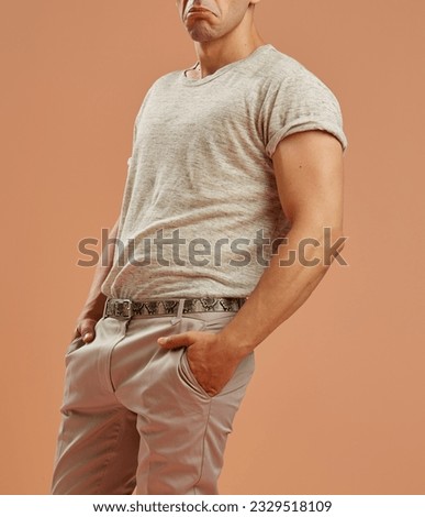 Young male model with casual clothes dancing slowly in front of a brown background 
