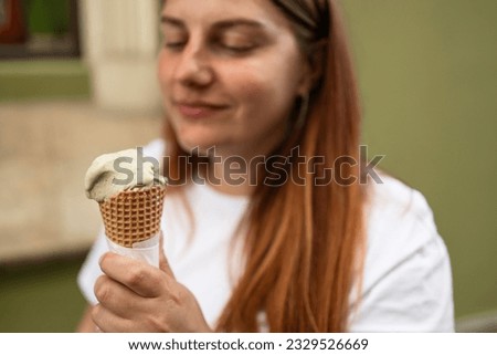 Happy young woman with delicious ice cream in waffle cone outdoors. Space for text. High quality photo