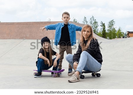 Beautiful young mom and little children boy and girl at the skatepark. Happy family spare weekends together