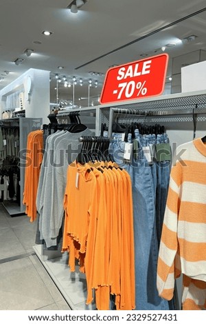 Sale sign and collection of stylish women's clothes in fashion store