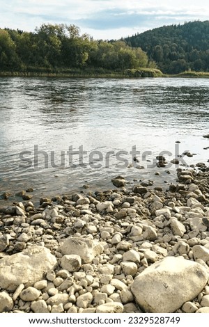 Ples on a mountain river in the early morning. Vishera Rivers of the Perm Territory. The morning rays of the sun illuminate the mountain peaks overgrown with forest. Rocky river bank. High quality Royalty-Free Stock Photo #2329528749