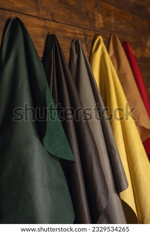 Genuine leather of different colors for the production of clothes and shoes hangs on a wooden wall. High quality photo