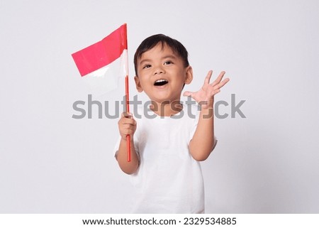 Excited toddler Asian kid boy celebrating Indonesian independence day on 17 August by raising fists isolated over white background Royalty-Free Stock Photo #2329534885