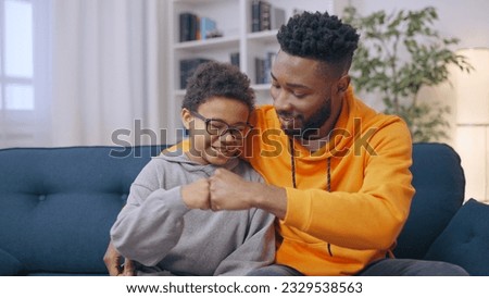 Two happy African American brothers bumping fists, siblings having fun together at home Royalty-Free Stock Photo #2329538563