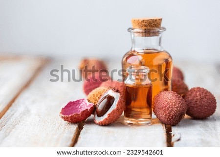 Glass bottles with pure organic essential litchi oil on wooden background. Concept of natural ingredients for beauty treatment, skin care, massage. Exotic fruit extract Royalty-Free Stock Photo #2329542601