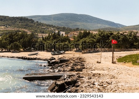 Quiet beach in Izmir, Turkey with juniper trees, Turkish Flag and wooden boats