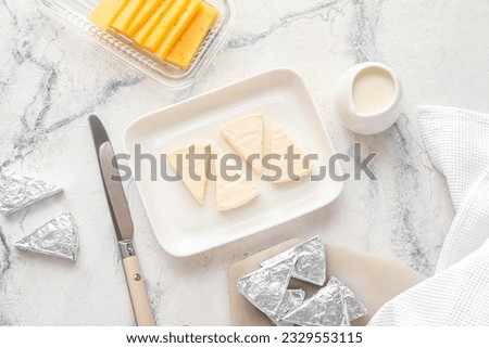 Plate with triangles of tasty processed cheese and milk on light background Royalty-Free Stock Photo #2329553115