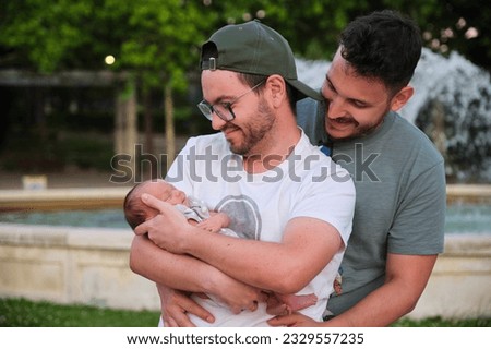 Gay happy couple with their newborn baby in a park. Four days old infant, parenthood concept. Royalty-Free Stock Photo #2329557235