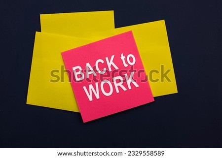 Back to work - inscription of a pink square sticky note paper on dark background. Top view. Business and marketing concept
