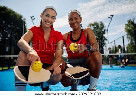 Happy women playing doubles in pickleball on outdoor court and looking at camera. Royalty-Free Stock Photo #2329591839