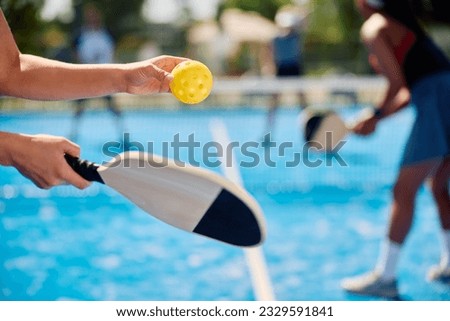 Close up of female player serving the ball while playing doubles in pickleball.  Royalty-Free Stock Photo #2329591841