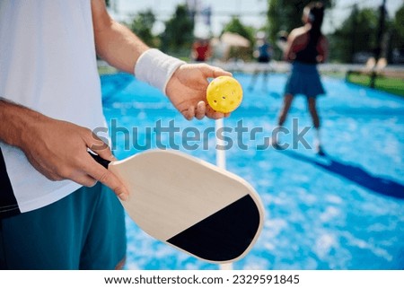 Close up of pickleball player serving the ball during the match on outdoor court. Royalty-Free Stock Photo #2329591845