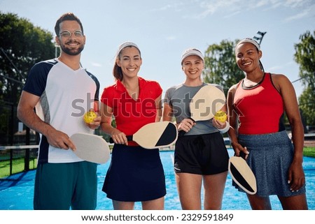 Group of happy athletic friends playing mixed doubles in pickleball and looking at camera. Royalty-Free Stock Photo #2329591849