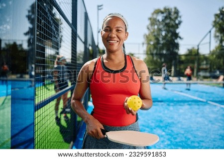 Happy African American woman playing pickleball on an outdoor court and looking at camera. Copy space. Royalty-Free Stock Photo #2329591853