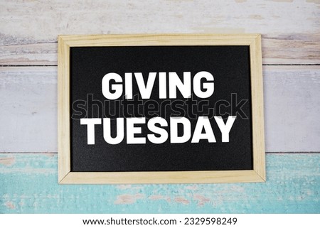 Giving Tuesday text on blackboard flat lay on wooden background