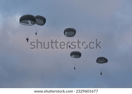 silhouettes of military paratroopers in the darkness of dawn on a cloudy day