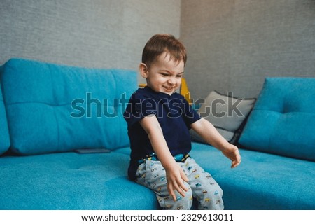 Two-year-old little boy sitting on the sofa at home, home entertainment of a small child.