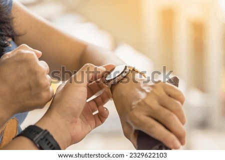 Closeup image of man use thumb finger teaching woman how to use application on smartwatch. Man teach woman how to use a smartwatch before exercise in the gym. Lifestyle technology concept for people.