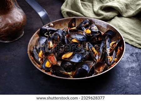 Traditional barbecue Italian blue mussel in tomato red wine sauce with herb and garlic as close-up in a rustic iron pan  Royalty-Free Stock Photo #2329628377