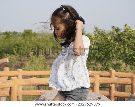 Amazing portrait image with smiling little brown haired girl. Concept happy and beauty kid with good healthy with blur background. Six year child wearing white and black in garden.