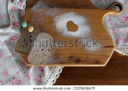 Two pieces of toast on a wooden board, sprinkled with flour. A heart-shaped pattern is visible in the flour. A delightful image suitable for food, baking, breakfast themes, and Valentine's Day.
