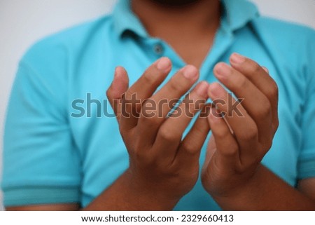Gesture of praying male hands on light blue t-shirt background
