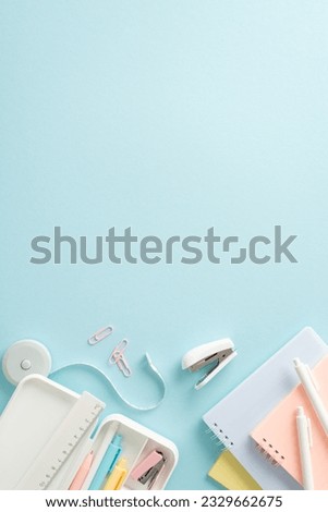 Fuel your educational journey with top vertical view picture displaying selection of stationery items, notepads and pencil case on blue backdrop. The empty circle allows for promotional material