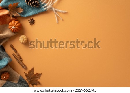 Welcome autumn vibes. Top view of warm blanket, miniature pumpkins, golden leaves, pine cone, cinnamon sticks, and star anise on an orange backdrop. Perfect for text or advertising