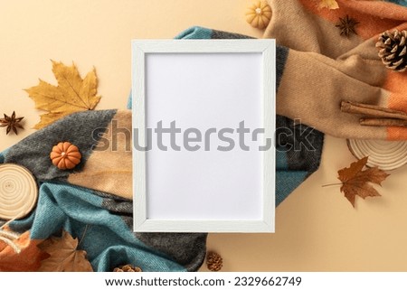 Fall in love with autumn: top view showcasing empty photo frame, plaid, pumpkins, golden maple leaves, pine cone, cinnamon, anise on beige backdrop. Promote effectively with this enchanting scene