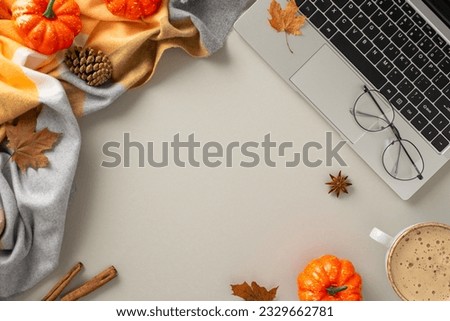 Top-down perspective encapsulates the working-from-home concept, featuring a laptop, cozy elements like blanket, pumpkins, pinecones, spices, glasses, coffee on isolated grey background and copyspace