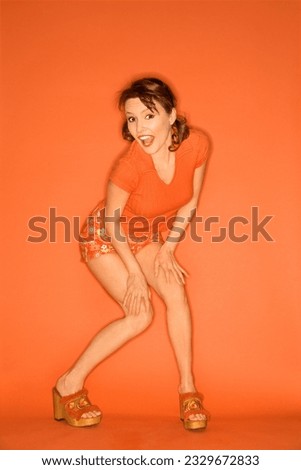 Caucasian mid-adult woman posing on orange background.