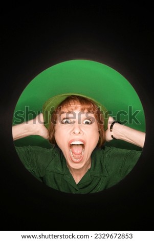 Vignette of Caucasian mid-adult woman with surprised expression wearing hat on green background.