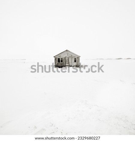 Abandoned house in snow covered landscape.