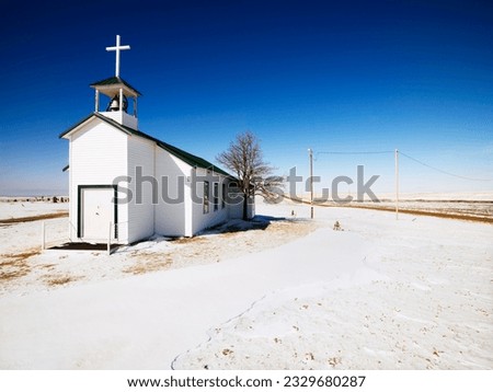 White small church with snow covered ground in foreground.